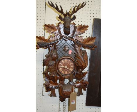A contemporary stained and carved walnut Swiss cuckoo clock, having twin weight driven movement