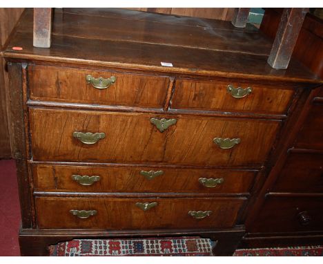 An 18th century oak and figured walnut veneered chest of two short over three long drawers, on bracket supports (with alterat