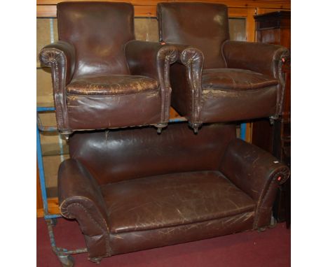 A pair of early 20th century tan leather upholstered and brass studded club armchairs, each raised on bun supports, width 85c