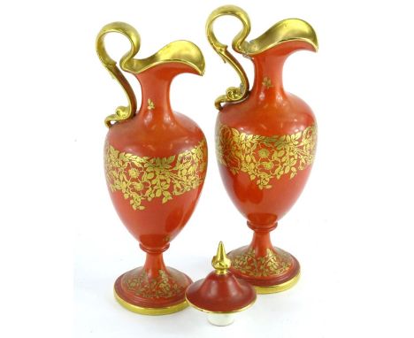 A pair of Royal Worcester porcelain ewers, each decorated in gilt with flowers, leaves etc., on a coral covered ground and an