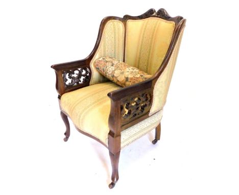 An Edwardian stained mahogany salon type armchair, with a padded back, sides and seat, fret work arm supports, on cabriole le