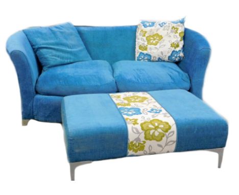 A modern blue upholstered two seater sofa, of shaped form, on metal feet, and a matching rectangular footstool, with floral i