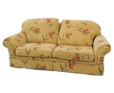 A modern sofa, upholstered in red floral fabric on a gold background.