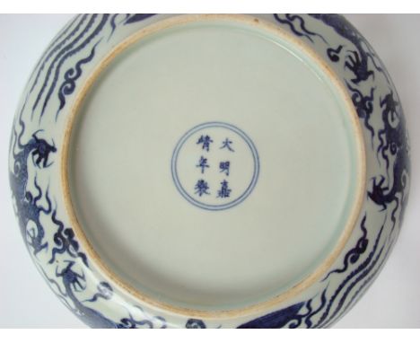 A large Chinese blue and white dragon and phoenix dish, with shallow sides and scalloped rim, the central medallion painted w