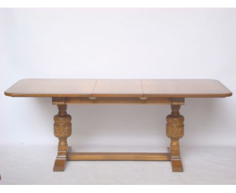 A light oak extending refectory table, the extending rectangular top on bulbous carved support on sledge bone united by a str