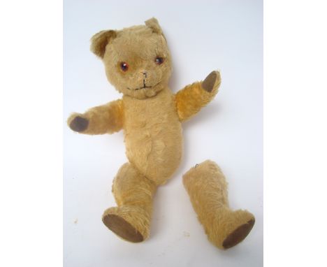 A straw filled English mohair teddy bear, with glass eyes and stitched nose, articulated limbs, one leg off, 55cm high. 