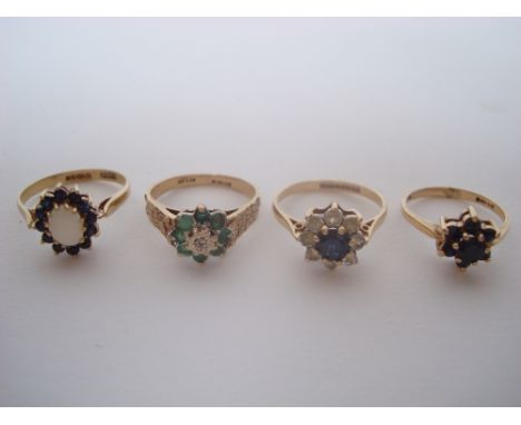 Four 9 carat dress rings to include an emerald and diamond cluster ring, a textured shank size N, sapphire flower cluster siz