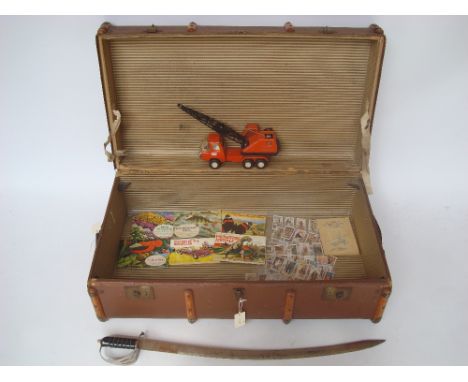 A wooden bound canvas cabin trunk, with an Indian sword, tea cards and a Tonka tin plate crane. 
