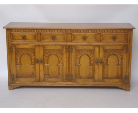 A light oak sideboard, with four fielded short drawers above two pairs of panelled cupboard doors carved with arches.
175 x 4