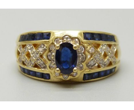 An 18ct gold cluster ring set with a central oval sapphire measuring approximately 0.53ct, twelve diamond surround weighing a