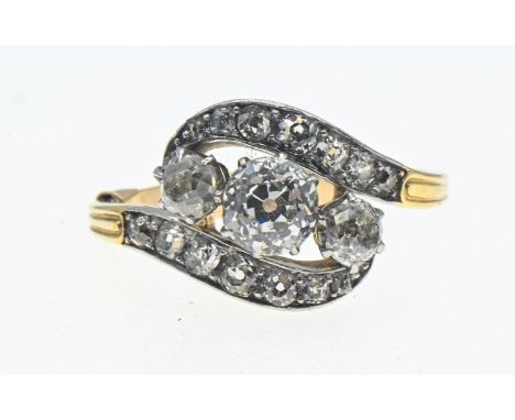 Diamond crossover ring with old European cut stones. Claw set with pavé set accents in white metal on a yellow metal shank. (