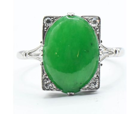 Jade and diamond ring. A Nephrite jade cabochon measuring approx. 14mm x 10mm in a rectangular setting with diamonds at each 