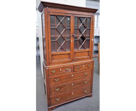 A mid-18th century provincial oak display cabinet chest with a pair of astragal glazed doors over two short and three long gr