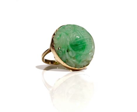 A 9ct gold mounted jade ring, the circular Asian jade with carved and pierced decoration, Birmingham 1984, ring size N, gross
