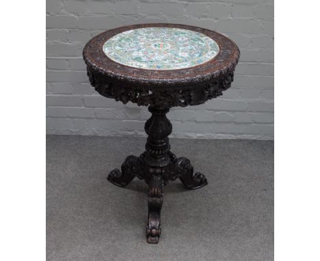 A 19th century Chinese export occasional table, the circular top inset with a ceramic famille verte panel, depicting interior