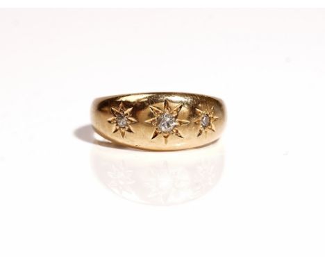 An 18ct gold and diamond set three stone ring, star gypsy set with a row of cushion shaped diamonds, Birmingham 1908, ring si