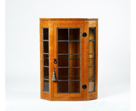 Robert Mouseman Thompson; A 20th century blonde oak hanging corner display cabinet with a trio of leaded glazed panels, 70cm 