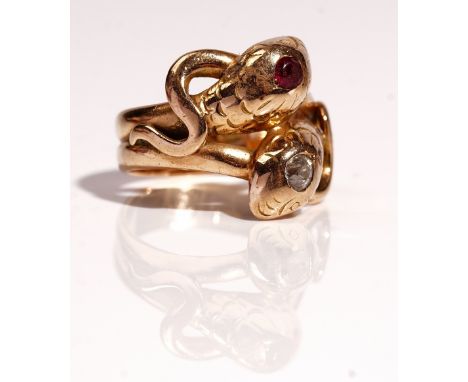 A gold, ruby and diamond ring, designed as two entwined snakes, mounted with a cushion shaped diamond and with a cushion shap