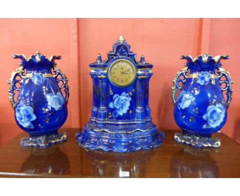 A Victorian Staffordshire porcelain clock garniture, painted with flowers on a cobalt blue ground and highlighted in gilt