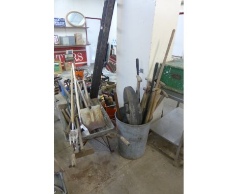 A galvanised bin, wheelbarrow and garden tools