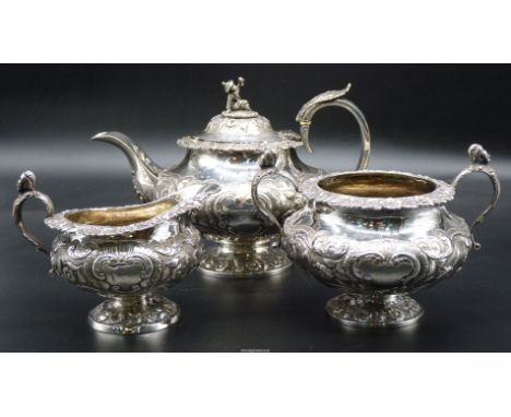 An ornate Silver three-piece Teaset profusely decorated in relief with scroll-work and trailing flowering stems and comprisin