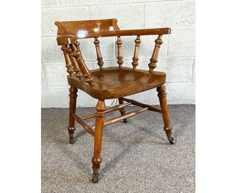 A Victorian ‘Smokers Bow’ oak armchair, with turned and scrolled back and set on ceramic castors