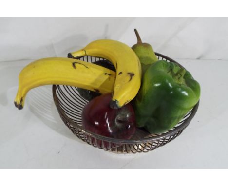 A silver plated bowl containing ceramic models of fruit and vegatables