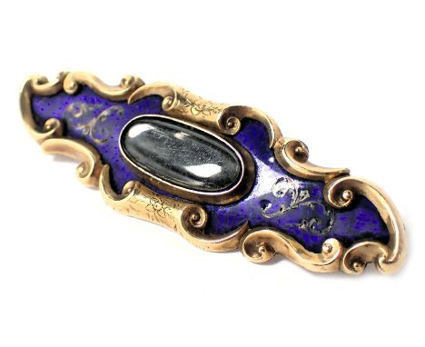 A Victorian memorial brooch, of elongated form set with blue enamel and raised scroll work, with a central oval memorial lock