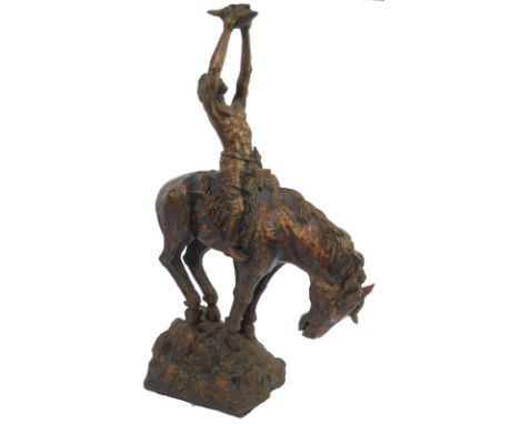 After Buck McCain. Native American resin figure with arms raised holding skull, on horseback, on rock work base, 68cm high. 