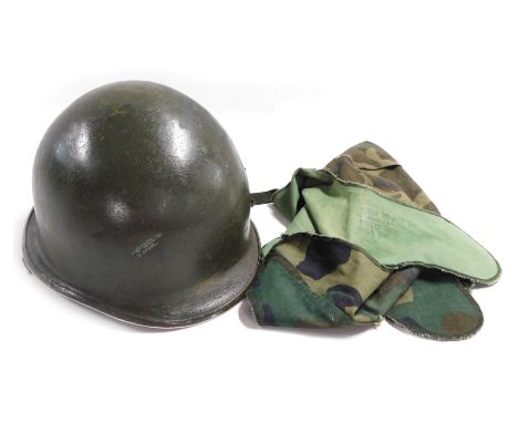 A WWII US Army steel helmet, with camouflaged cloth cover.
