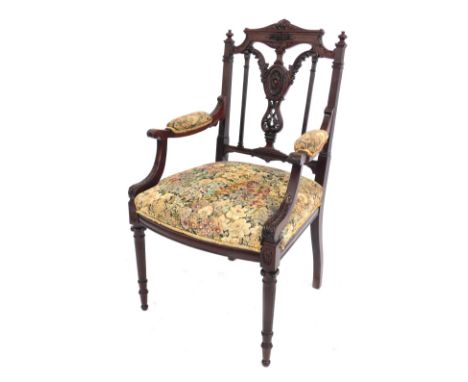 A late Victorian mahogany open armchair, with carved cresting rail and splat back, padded arms and over upholstered seat, in 