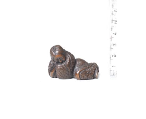 A wood netsuke of a sleeping ShojoBy Ikkan (1817-1893), Nagoya, 19th centuryLying with his head resting on his right hand, hi