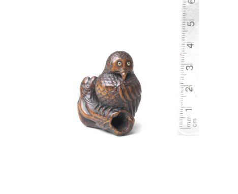 A wood netsuke of an owl19th centuryThe owl seated on a branch, turning its head to the left, bearing an alert expression, th