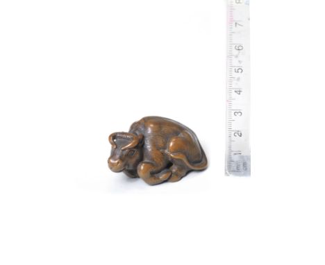 A wood netsuke of a recumbent oxBy Kokei, Kuwana, Ise Province, late 18th centuryThe ox lying, its legs drawn in, forming a c