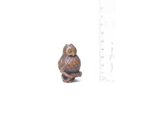 A wood netsuke of an owlSecond half of the 19th centuryThe owl perched on a short bifurcated branch, foliage attached to the 