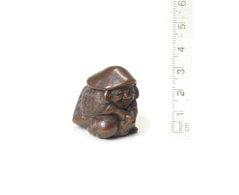 A compact wood netsuke of DaikokuBy Nobuyuki, 19th centuryDaikoku with a bemused expression, crouching over a captured thief 