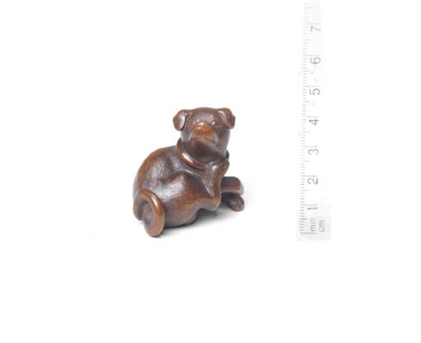 A boxwood netsuke of a dog19th centuryThe dog seated, wearing a knotted collar, its head turned back to the right, its hind p