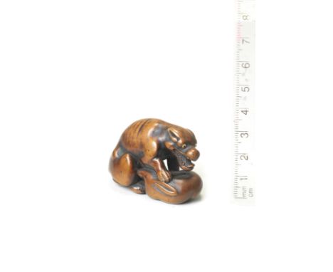 A wood netsuke of a wolfAfter Okatomo, Kyoto, early 19th centuryThe wolf seated, leaning forward with an open mouth, one fore