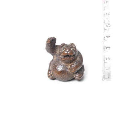 A wood netsuke of a tanukiBy Tanaka Minko (1735-1816), Tsu, late 18th centuryThe tanuki seated, its right foreleg raised, its