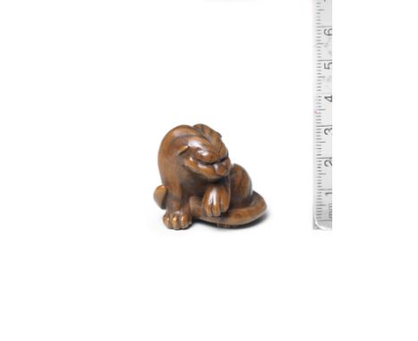A boxwood netsuke of a tigerBy Masataka, early 19th centuryThe tiger seated, its head lowered to the left, licking its raised