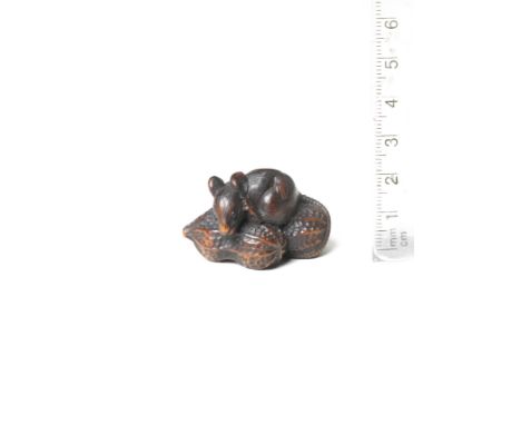 A wood netsuke of a rat on peanutsMid-19th centuryThe rodent sitting upon two peanuts and scratching its ear with its left hi