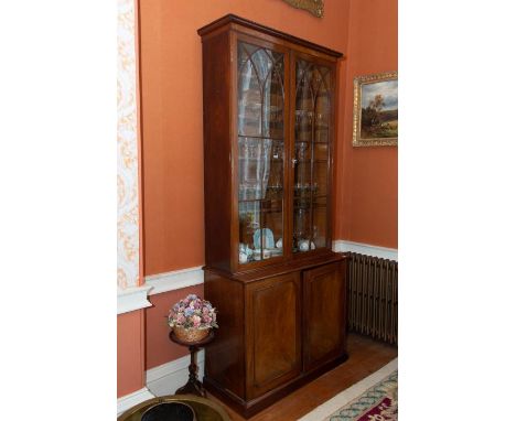 A mahogany bookcase cabinet, 19th century, with upper narrow astragal glazed doors, reeded pilasters, over a base with cupboa