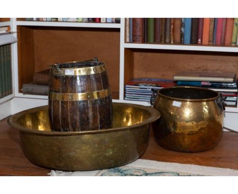 A coopered wood and brass bound ovoid bucket, of barrell shape with swing handle, 45cm high. A large heavy gauge brass basin,