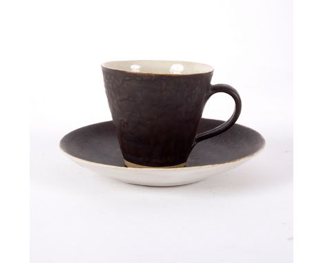 Lucie Rie (1902-1995), a teacup and saucer, in manganese glaze with cream interior, impressed mark, the cup 6cm high, the sau