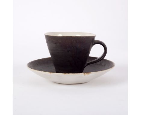 Lucie Rie (1902-1995), a teacup and saucer, in manganese glaze with cream interior, impressed mark, the cup 6cm high, the sau