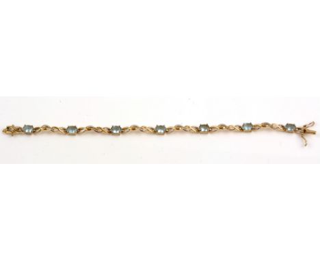 Topaz bracelet, set with seven oval facet cut light blue topaz, silver gilt mounts and scrolling links, 19cms long.