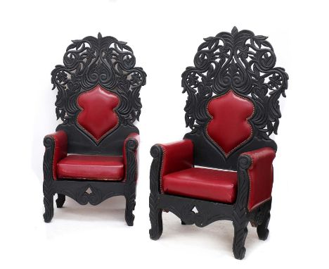HORROR THRONES,late 20th century, a pair of carved and patinated wooden thrones, each seat and back upholstered in red vinyl 