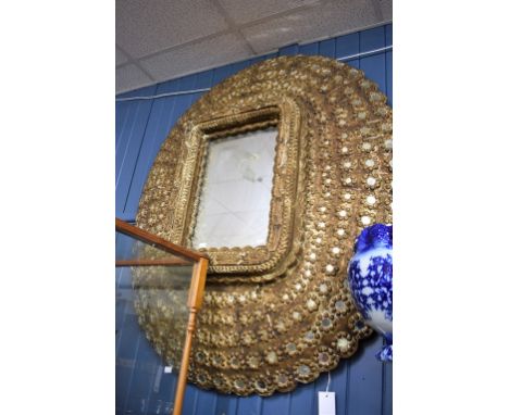 A large scale Moorish carved gilt wood peacock mirror inset with a multitude of small mirrors.