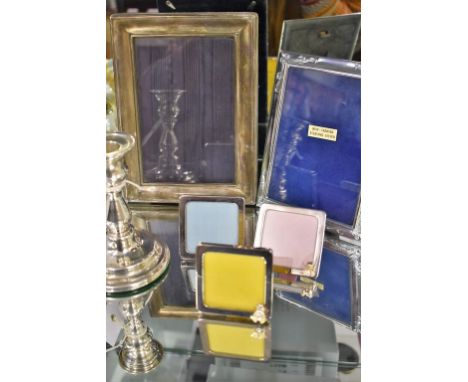 A collection of silver items to include five photo frames of varying dates and sizes, together with a candlestick.