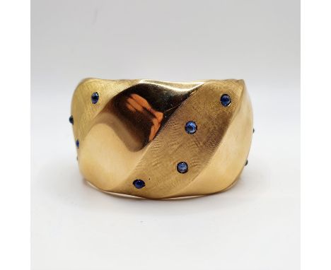 An 18ct gold, and blue stone bangle, 75.4gAt widest point 63mm wide 